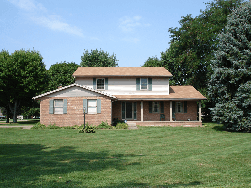 Exterior of white and redish brick house with lawn