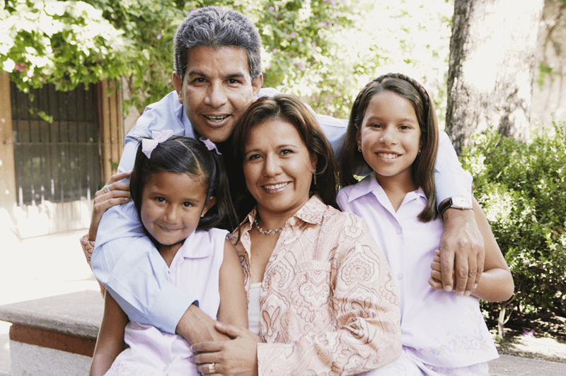 Family of 4 smiling with arms around each other